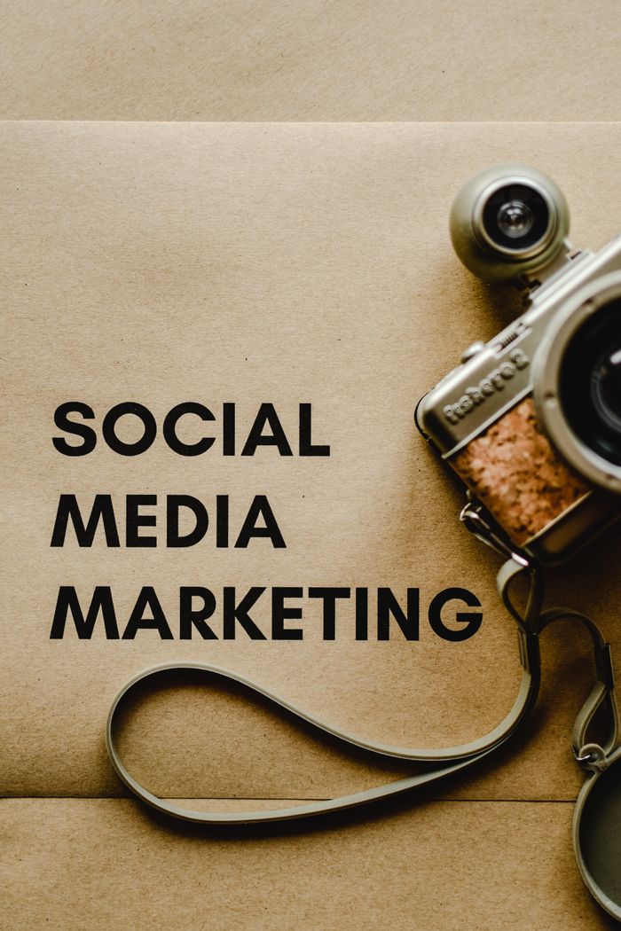 about-us-01 Vue rapprochée d’un appareil photo vintage à côté d’un texte de concept de marketing sur les réseaux sociaux sur fond marron.